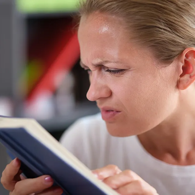 A person squinting while reading a book