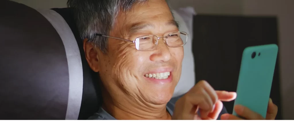 Man wearing eyeglasses and smiling while using his cellphone