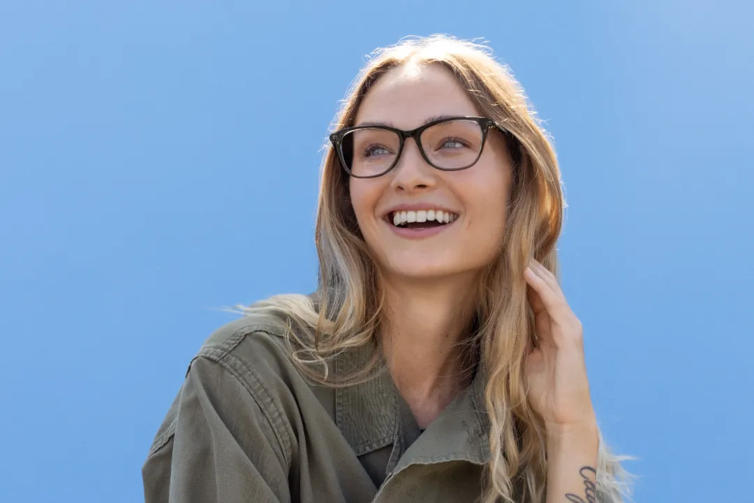 smiling woman wearing toms eyewear in blue background