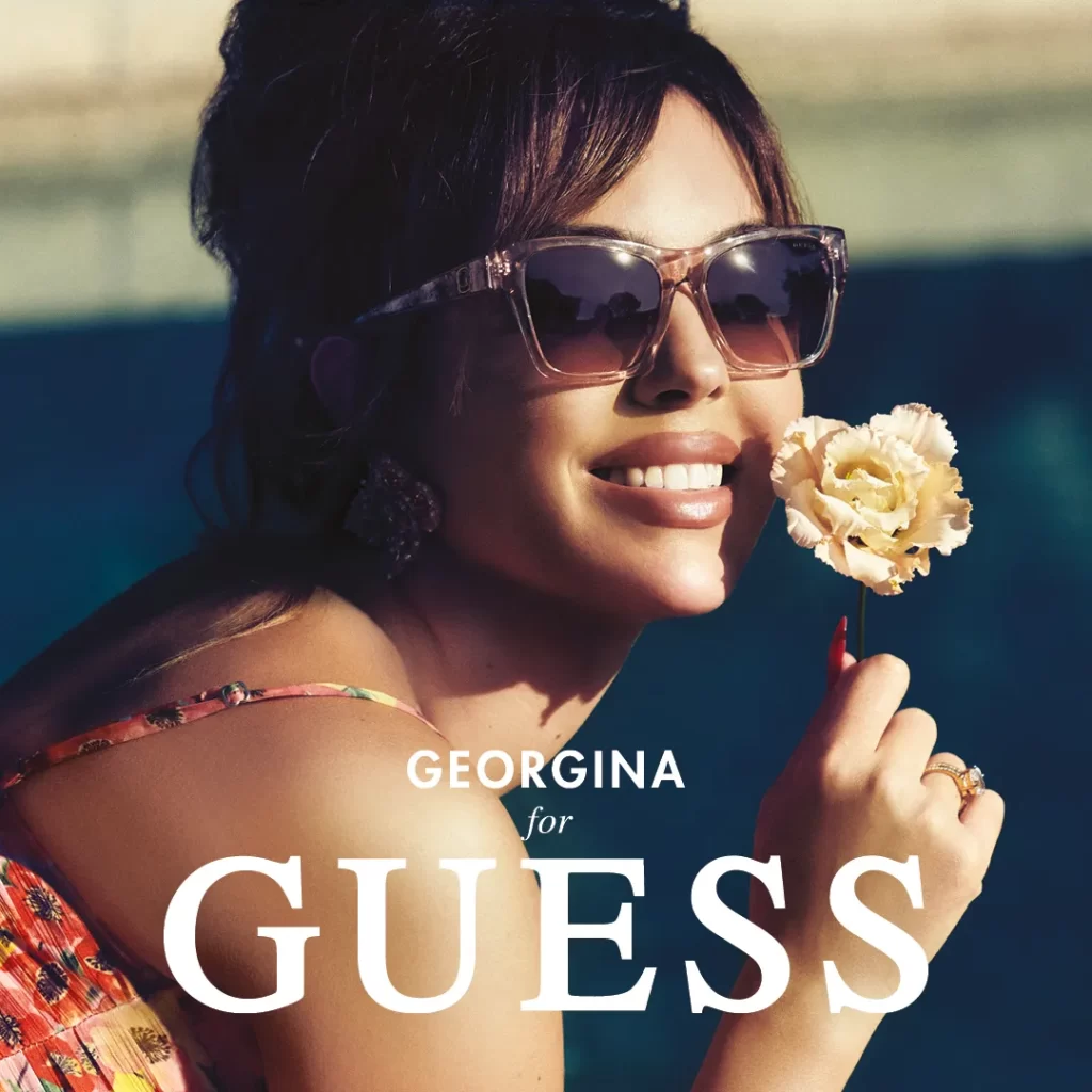 georgina holding a flower and wearing guess sunglasses